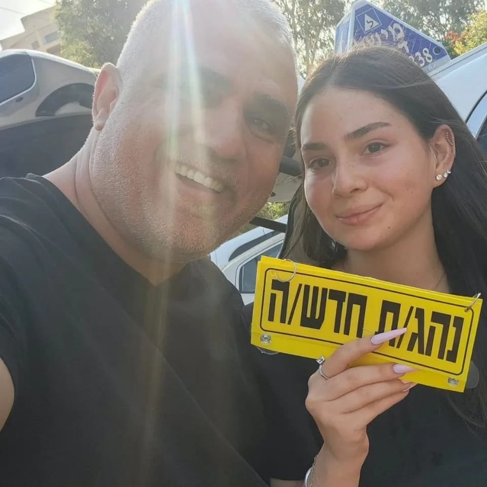 תלמידה מחזיקה שלט נהג חדש לצד מישל דנינו