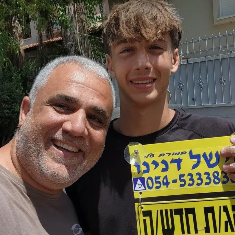 תלמידה מחזיקה שלט נהג חדש לצד מישל דנינו