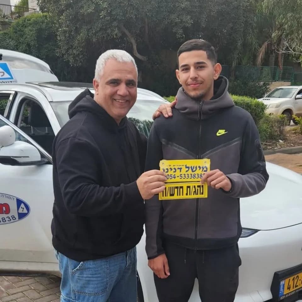 תלמיד מחזיק שלט נהג חדש לצד מישל דנינו