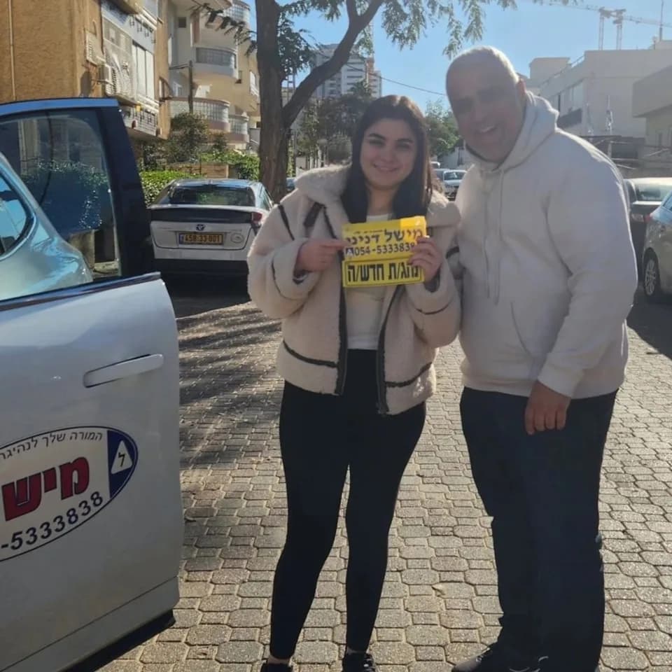 תלמיד מחזיק שלט נהג חדש לצד מישל דנינו