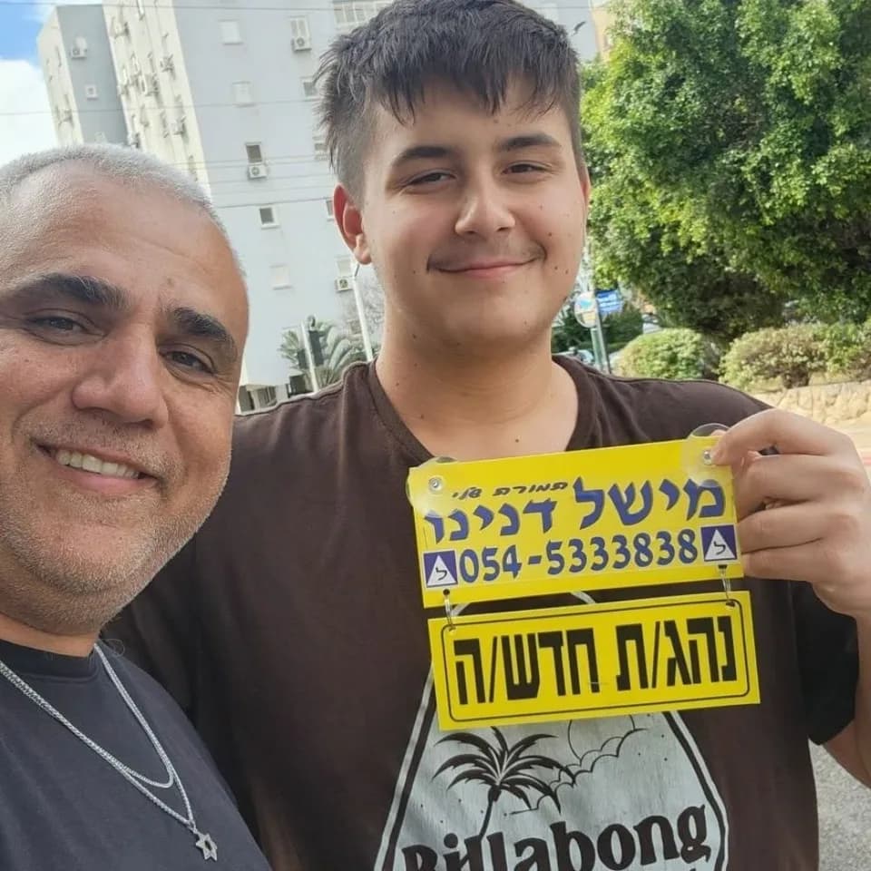 תלמיד מחזיק שלט נהג חדש לצד מישל דנינו