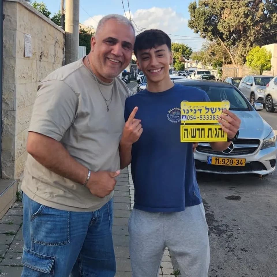 תלמיד מציג שלט נהג חדש לצד מישל דנינו